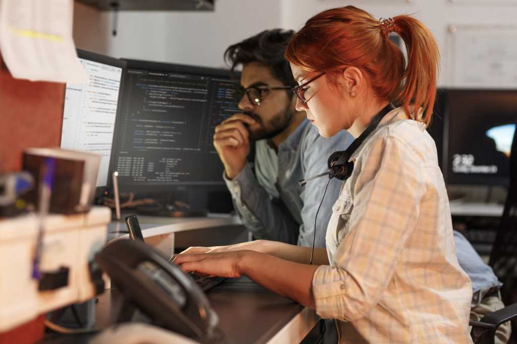 Two programmers working on new project.They working late at night at the office.