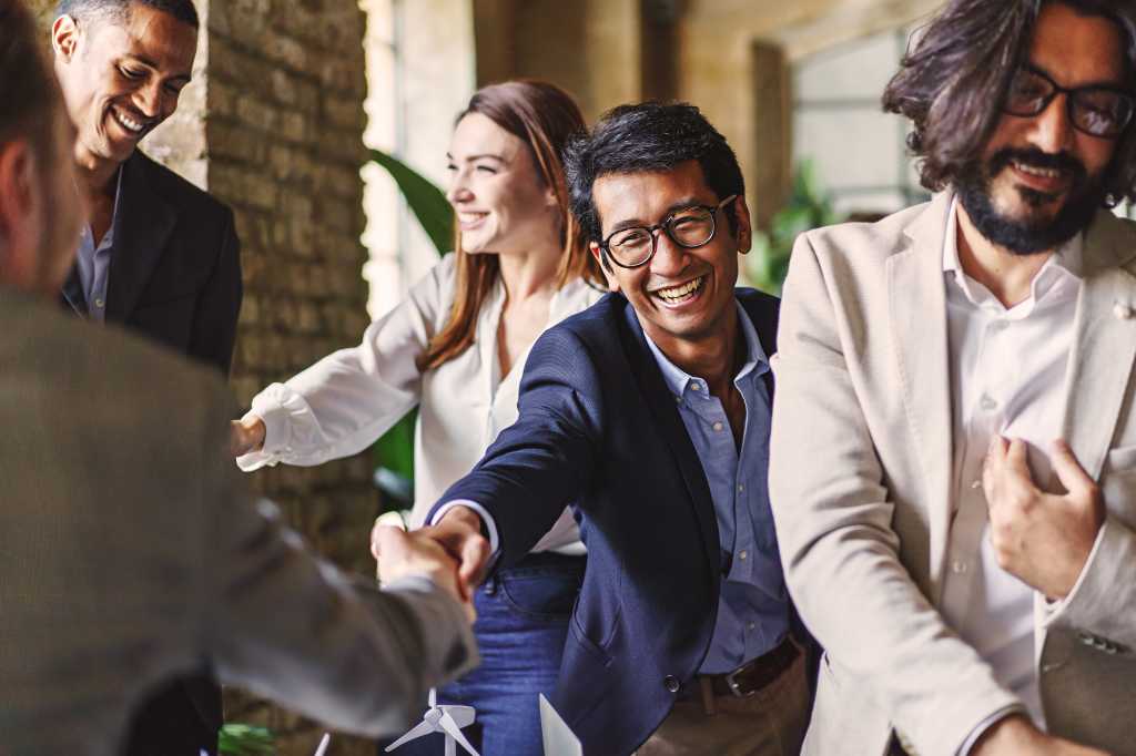 Networking. Group of diverse professionals celebrating with a handshake at a corporate event, embodying teamwork and achievement.