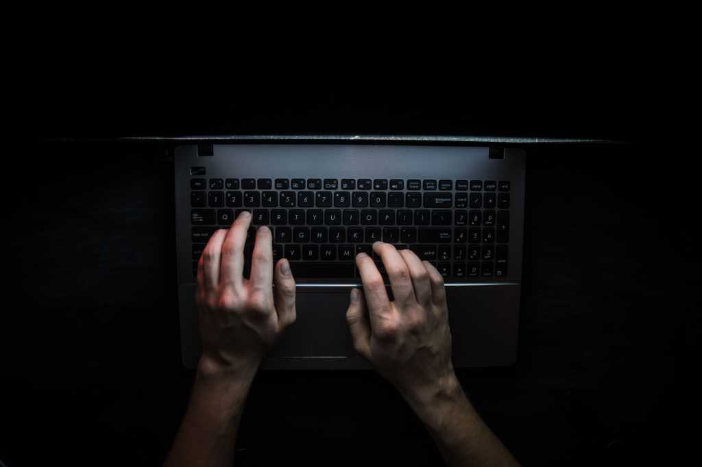 hands typing on laptop in dark setting