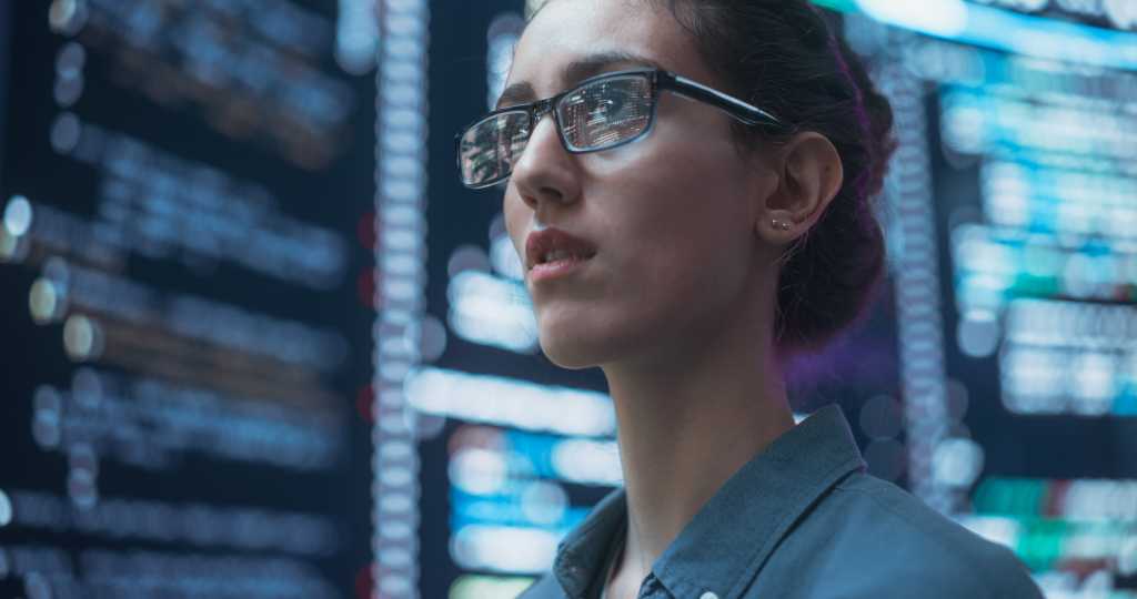 Close Up Portrait of Woman Working on Computer, Lines of Code Language Reflecting on her Glasses from Big Display Screens. Female Programmer Developing New Software, Coding, Managing Cybersecurity