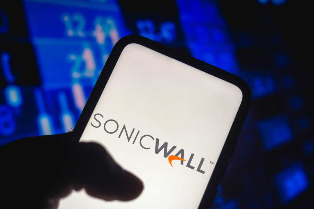 A silhouetted hand holding a smartphone, with the SonicWall logo displayed on the screen.