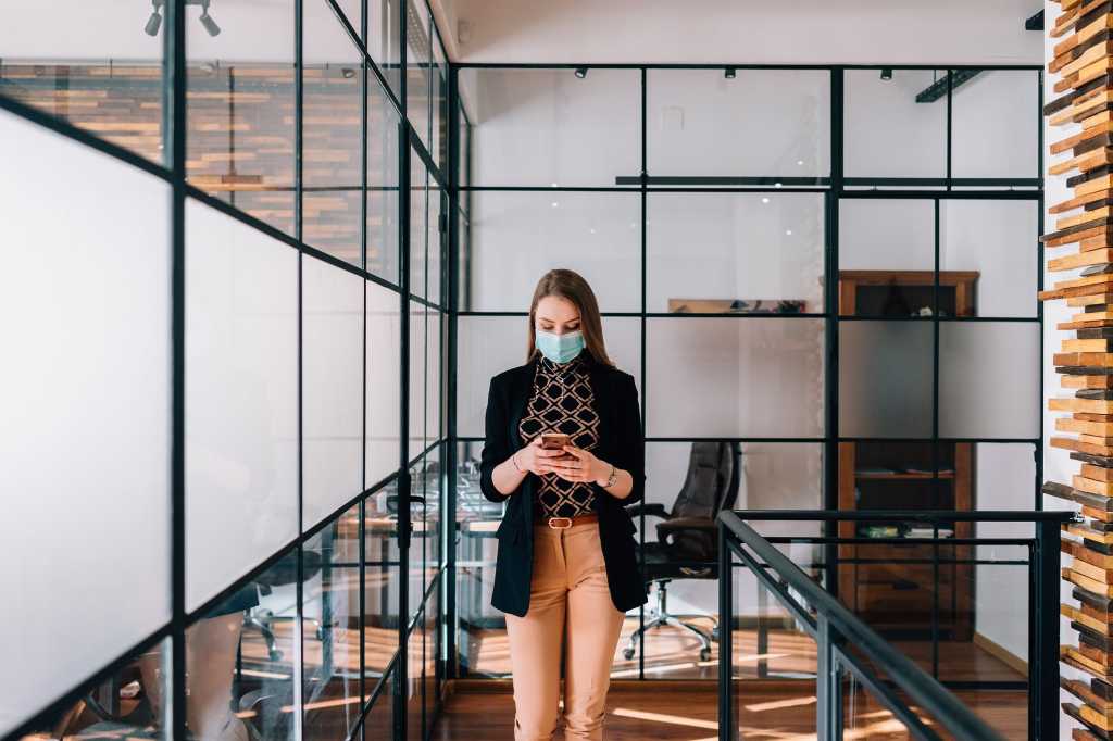 A businesswoman wears a protective mask in an office.  >  protection from viruses/pollutants/toxins