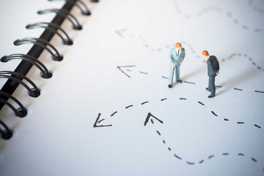 two tiny figures study dashed lines with arrows indicating different directions or paths