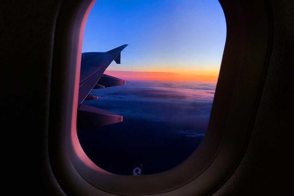 Passenger view of an airplane wing above the clouds. / travel / journey / transportation