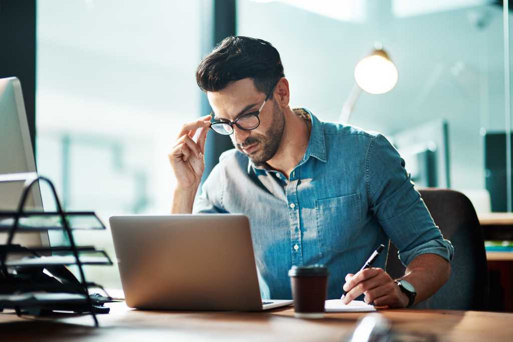 Serious, planning and professional manager reading emails and schedule appointments. Businessman doing online research and writing reports trying to reach deadline during overtime in a startup